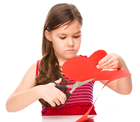 Image showing Portrait of a little girl cutting out red heart