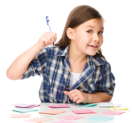 Image showing Girl is writing on color stickers using pen