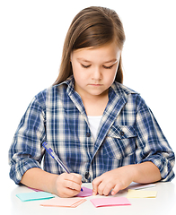 Image showing Girl is writing on color stickers using pen