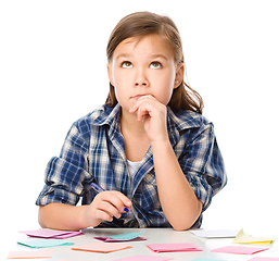 Image showing Girl is writing on color stickers using pen