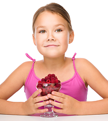 Image showing Happy little girl is eating raspberries