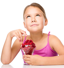 Image showing Happy little girl is eating raspberries