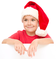 Image showing Little girl in santa hat is holding blank board