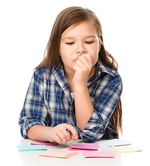 Image showing Girl is writing on color stickers using pen