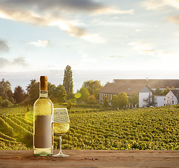 Image showing Glass and bottle of wine on wooden rail with country rural scene in background