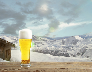 Image showing Single light beer in glass and landscape of mountains on background