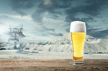 Image showing Single light beer in glass and landscape of mountains on background