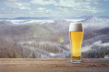 Image showing Single light beer in glass and landscape of mountains on background