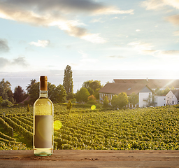 Image showing Bottle of wine on wooden rail with country rural scene in background