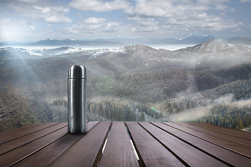 Image showing Thermos with tea or coffee and landscape of mountains on background