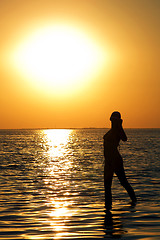Image showing Silhouette of the young woman on a bay on a sunset