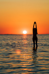 Image showing Silhouette of the young woman with hands upwards on a bay on a s