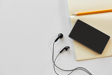 Image showing earphones, smartphone and notebook with pencil