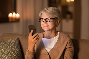 Image showing happy senior woman with smartphone at home