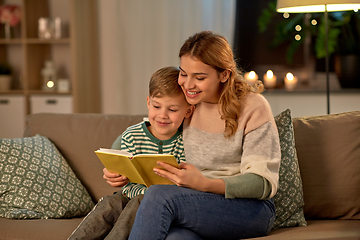 Image showing happy mother and son reading book sofa at home