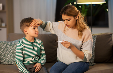 Image showing sad mother with thermometer and ill son at home