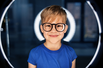 Image showing boy in glasses over illumination in dark room