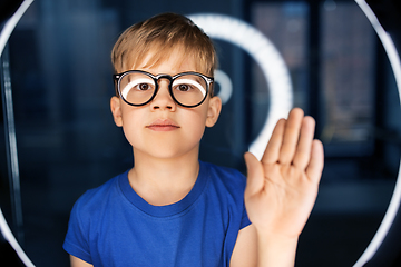 Image showing boy in glasses over illumination in dark room