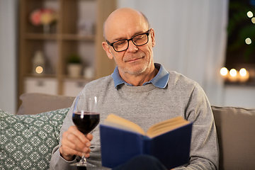 Image showing happy senior man drinking wine and reading book