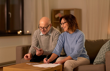 Image showing senior couple with bills counting money at home