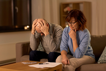 Image showing unhappy senior couple with bills and money at home