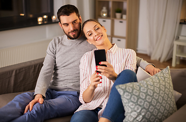 Image showing happy couple with smartphone taking selfie at home