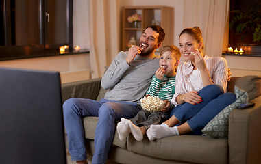 Image showing happy family with popcorn watching tv at home