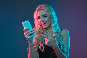 Image showing Caucasian young woman\'s portrait on gradient background in neon light