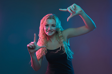 Image showing Caucasian young woman\'s portrait on gradient background in neon light