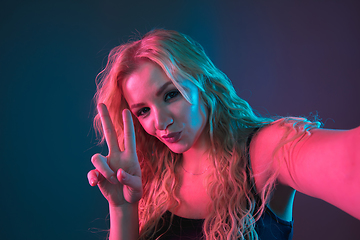 Image showing Caucasian young woman\'s portrait on gradient background in neon light