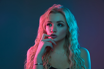 Image showing Caucasian young woman\'s portrait on gradient background in neon light