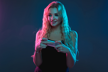 Image showing Caucasian young woman\'s portrait on gradient background in neon light