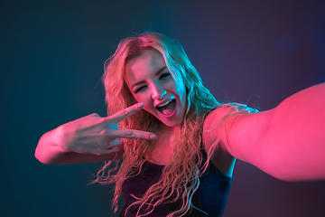 Image showing Caucasian young woman\'s portrait on gradient background in neon light