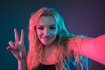 Image showing Caucasian young woman\'s portrait on gradient background in neon light