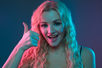 Image showing Caucasian young woman\'s portrait on gradient background in neon light