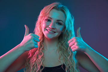 Image showing Caucasian young woman\'s portrait on gradient background in neon light