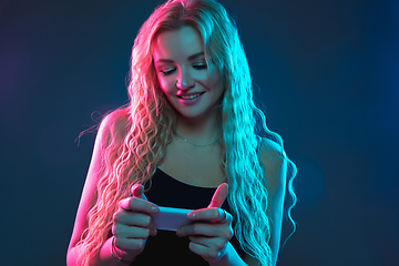 Image showing Caucasian young woman\'s portrait on gradient background in neon light