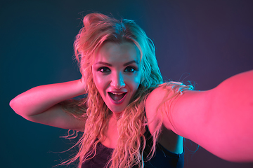 Image showing Caucasian young woman\'s portrait on gradient background in neon light