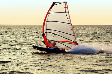 Image showing Silhouette of a windsurfer on a gulf, moving at great speed