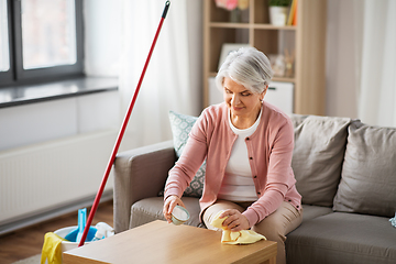 Image showing senior woman cleaning table with soda at home