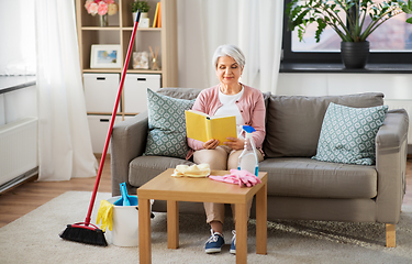 Image showing senior woman reading book after home cleaning