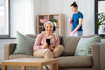 Image showing old woman in headphones with smartphone at home