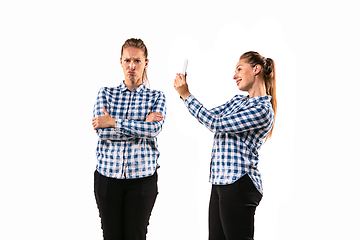 Image showing Young handsome woman arguing with herself on white studio background.