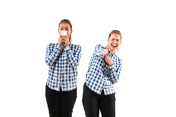 Image showing Young handsome woman arguing with herself on white studio background.