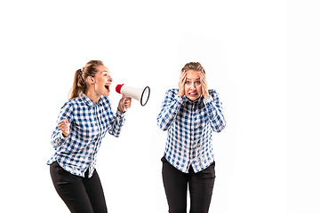 Image showing Young handsome woman arguing with herself on white studio background.