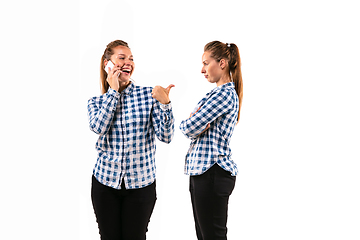 Image showing Young handsome woman arguing with herself on white studio background.