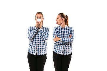 Image showing Young handsome woman arguing with herself on white studio background.