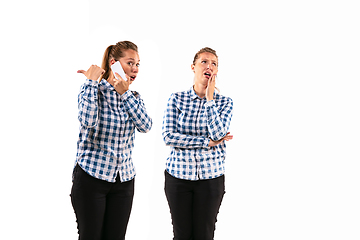 Image showing Young handsome woman arguing with herself on white studio background.