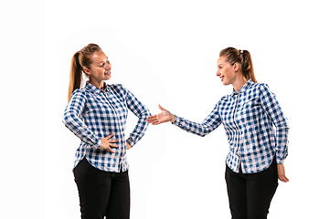 Image showing Young handsome woman arguing with herself on white studio background.