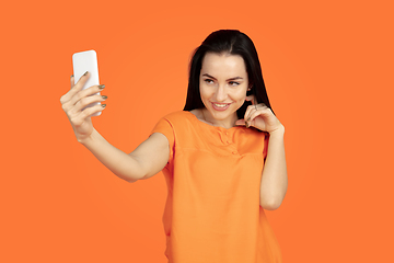 Image showing Caucasian young woman\'s portrait on orange background